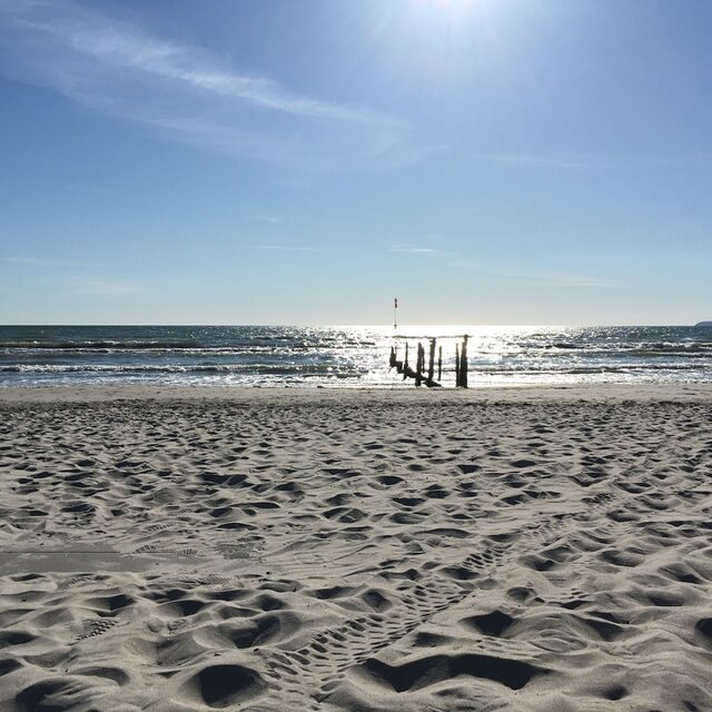 Sonnenlicht über dem ruhigen Sandstrand mit Blick auf die Ostsee.