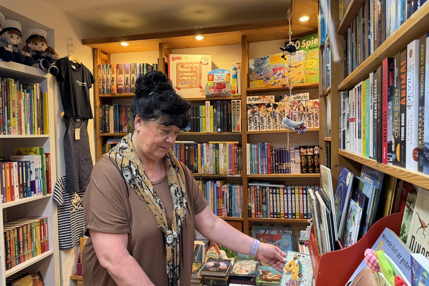 Eine Frau stöbert in einem bunt gefüllten Bücherregal der Strandgut Buchhandlung.
