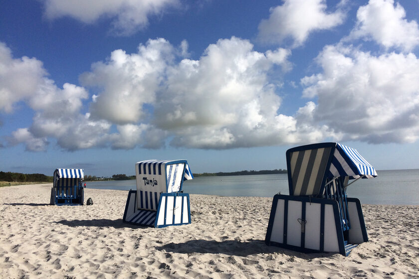 Zwei blau-weiß gestreifte Strandkörbe stehen am Strand von Juliusruh.