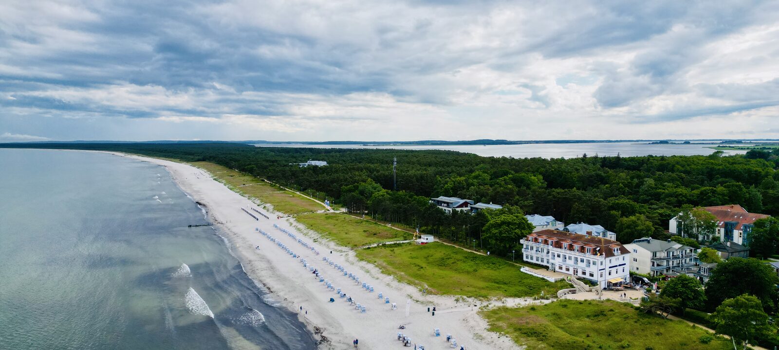 Luftbild der Küste von Juliusruh mit Sandstrand, Strandkörben und den Häusern am Ortsrand.